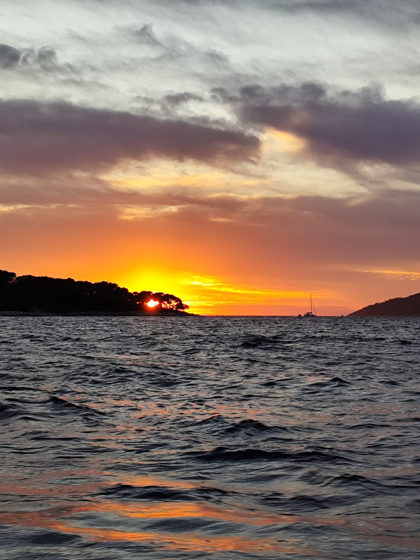 The sun setting behind a Pakleni island, golden light on the waves